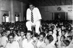M.H.M. Ameen being carried to the stage at the Assembly of Zahira       College, Colombo after winning the Queens Cup for the best marksman in        the country in 1957. He was the first schoolboy to win this prize.
